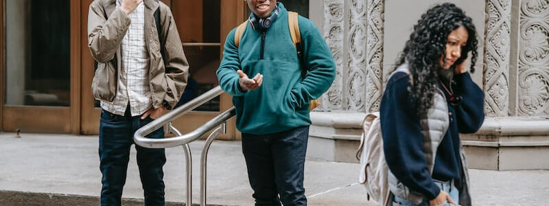 מתבגרת עם חרדה חברתית הולכת עם הגב מופנה אל שני נערים, אשר מדברים עליה מאחורי גבה.