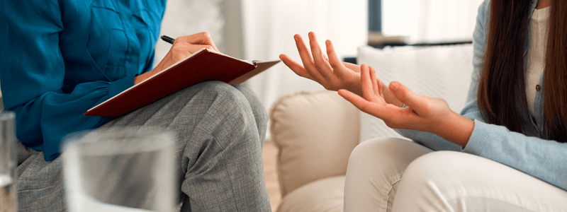 התמונה מציגה תקריב של מפגש טיפולי בין שני אנשים.