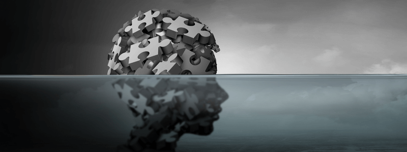 ראש מורכב מחלקי פאזל שקוע חלקית במים, המסמל מורכבות נפשית והתבוננות פנימה.