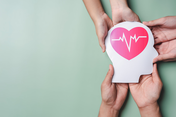 צורה של ראש במרכזה יש איור של לב ורוד עם קו של דופק בלבן, המסמל בריאות נפשית