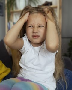 ילדה תופסת את ראשה ומעוותת את פניה 
